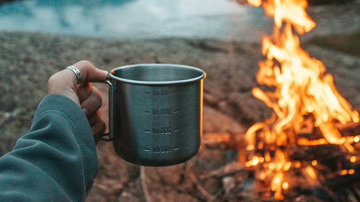 woman holding cup at campfire